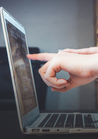 Persona tocando la pantalla de un ordenador portátil.